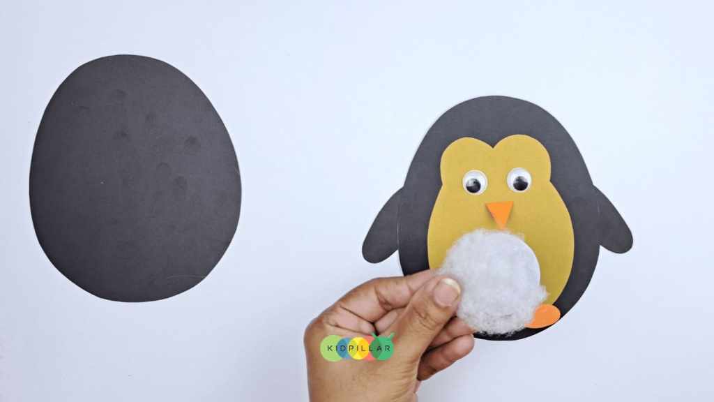 Paste cotton to make fluffy belly of moving paper penguin craft for preschoolers