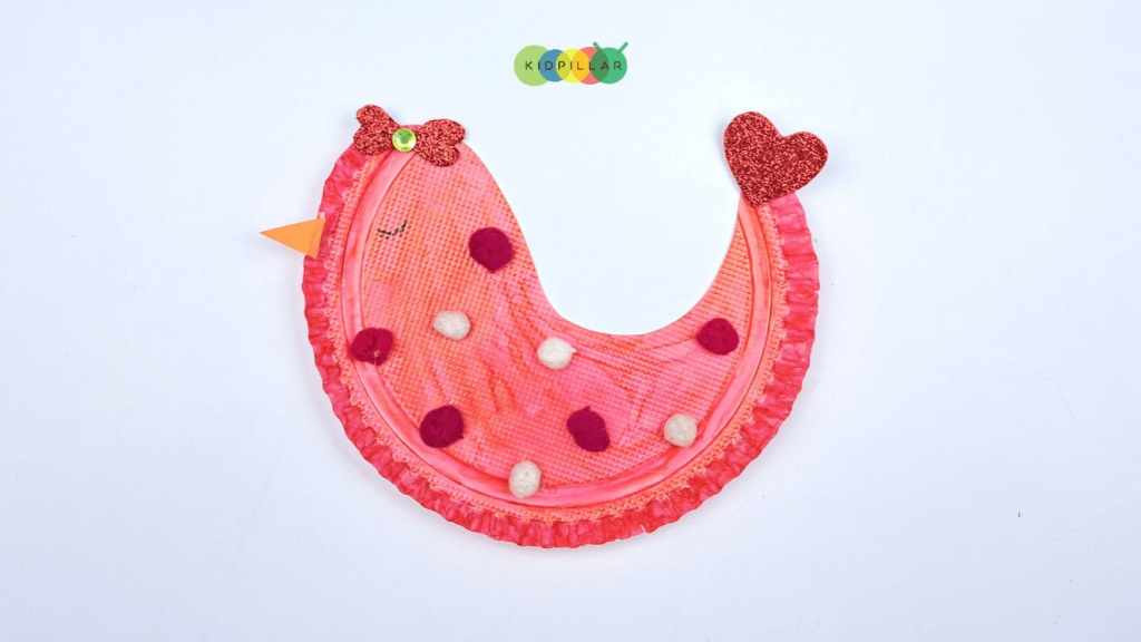 Glue pom-poms on rocking love birds craft with paper plate